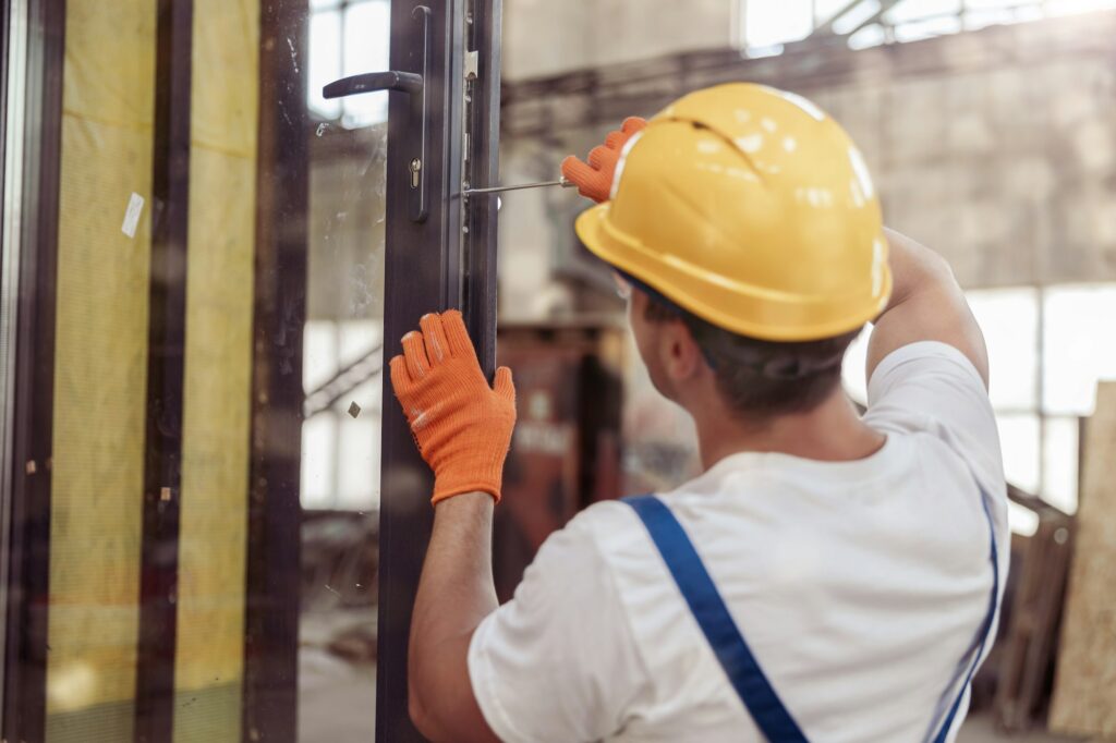 Male builder repairing door in building under construction